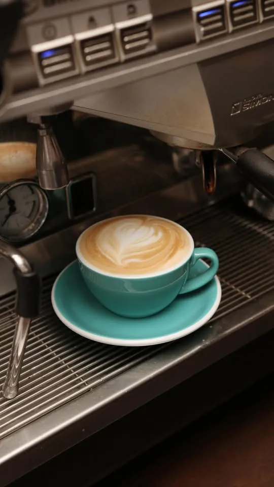 Kafija tirkīza krūzē uz espresso automāta